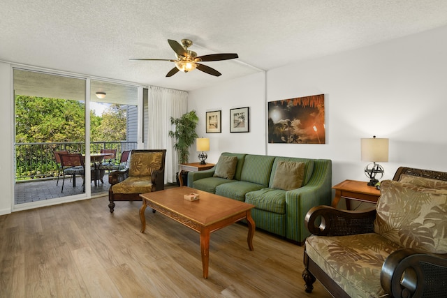 living room with ceiling fan, expansive windows, light hardwood / wood-style floors, and a textured ceiling