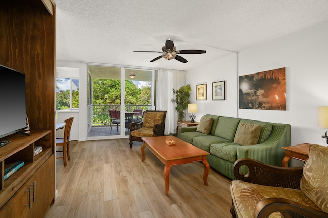 living room featuring light wood-type flooring, a textured ceiling, expansive windows, and ceiling fan