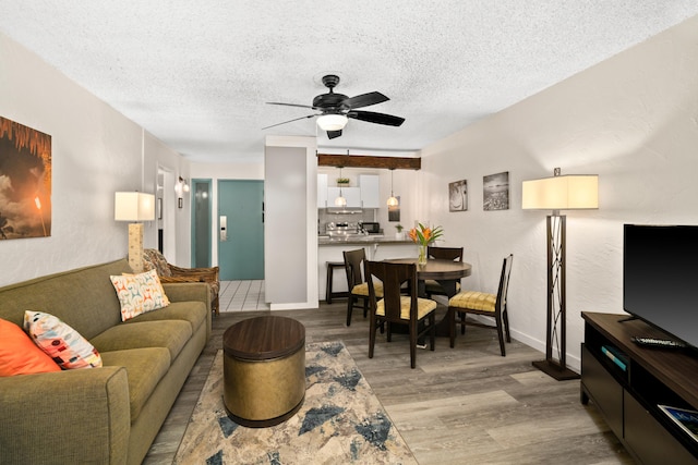 living room featuring ceiling fan, light hardwood / wood-style floors, and a textured ceiling