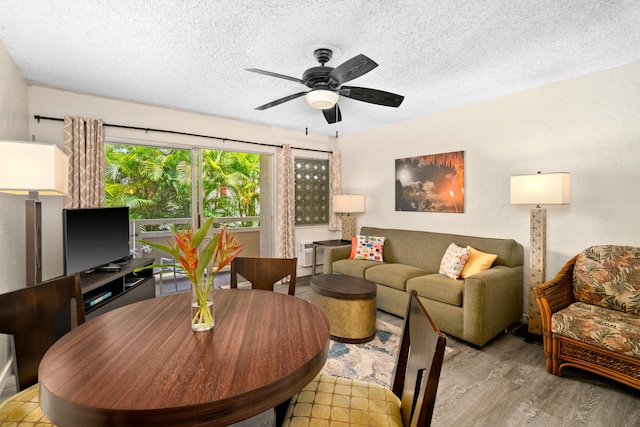 living room with ceiling fan, light hardwood / wood-style floors, and a textured ceiling