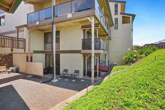 rear view of property featuring a balcony, a patio, and an outdoor hangout area