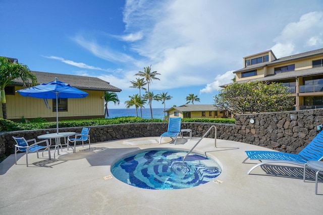 view of pool featuring a patio, a water view, and a hot tub