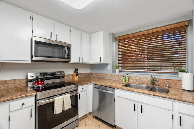 kitchen featuring sink, stainless steel appliances, light tile patterned floors, a textured ceiling, and white cabinets