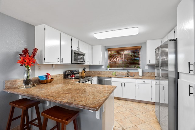 kitchen with kitchen peninsula, stainless steel appliances, white cabinets, and sink