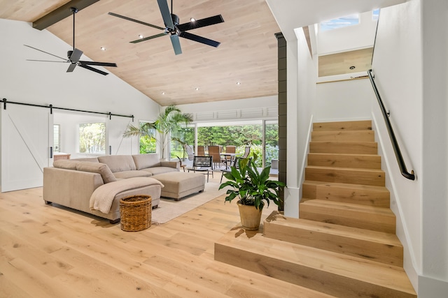 living room featuring light wood-type flooring, a barn door, ceiling fan, and wooden ceiling