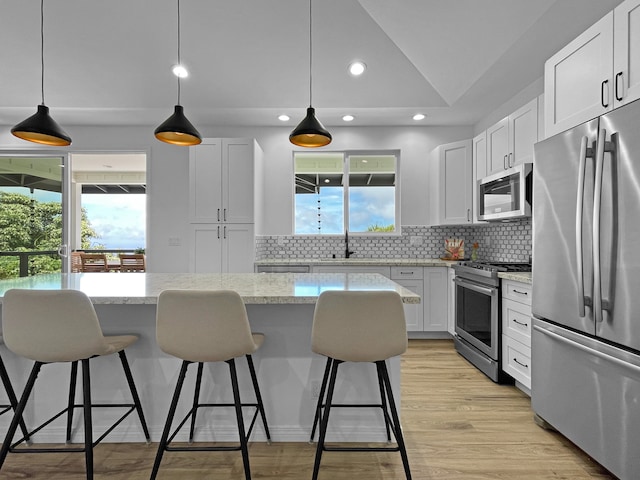 kitchen with decorative backsplash, appliances with stainless steel finishes, light wood-type flooring, and a wealth of natural light