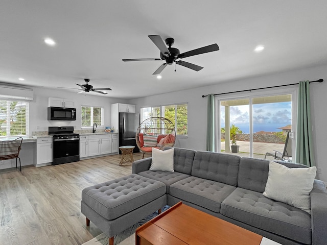 living room featuring light hardwood / wood-style floors, ceiling fan, and plenty of natural light