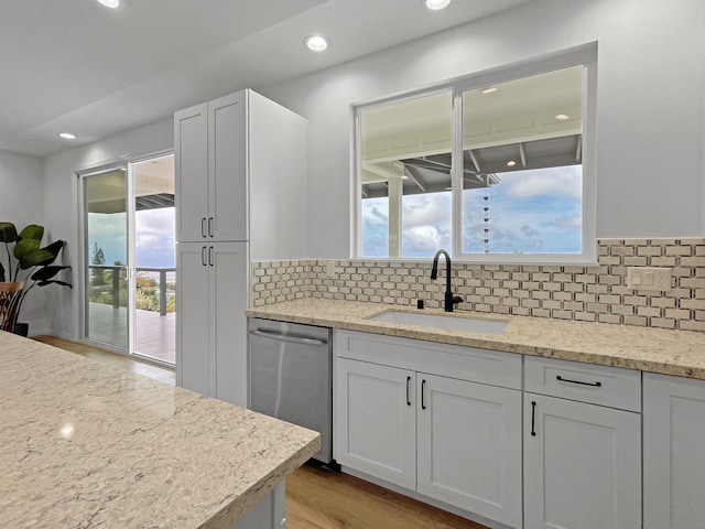 kitchen with backsplash, light hardwood / wood-style floors, dishwasher, and sink