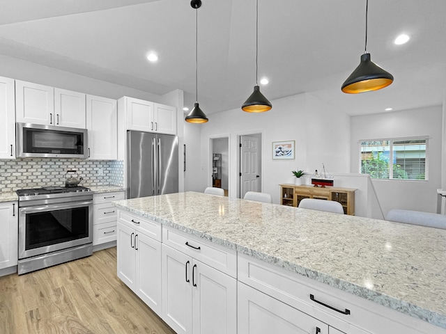 kitchen featuring tasteful backsplash, light hardwood / wood-style flooring, appliances with stainless steel finishes, and hanging light fixtures