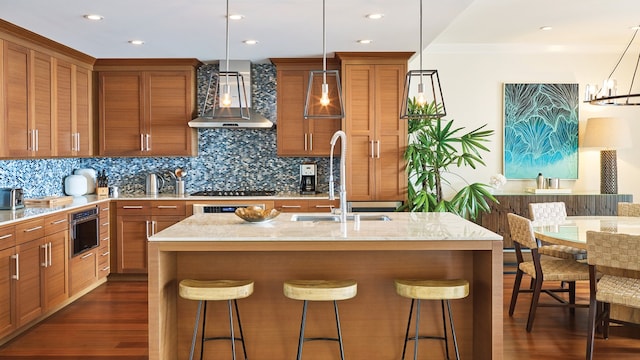 kitchen featuring dark hardwood / wood-style floors, a center island with sink, backsplash, wall chimney exhaust hood, and sink