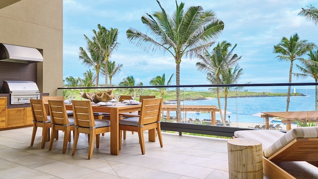 balcony with exterior kitchen, a grill, and a water view