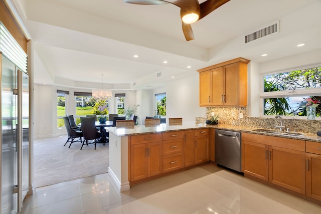 kitchen with sink, stainless steel appliances, kitchen peninsula, light carpet, and ceiling fan with notable chandelier