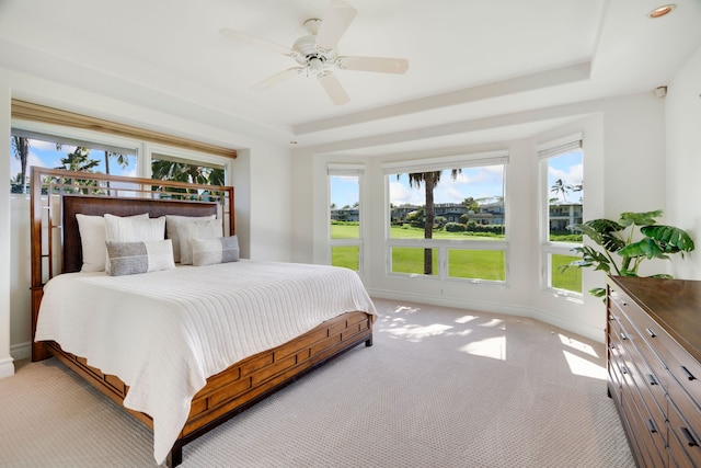 carpeted bedroom featuring a raised ceiling and ceiling fan