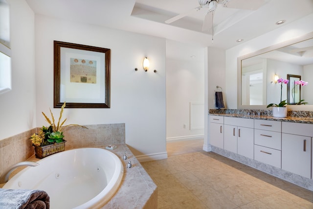 bathroom with vanity, a relaxing tiled tub, a raised ceiling, and ceiling fan