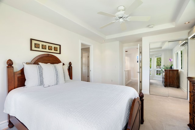 bedroom with a tray ceiling, ceiling fan, a closet, and light carpet