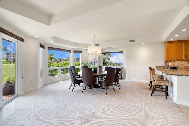 carpeted dining space with a raised ceiling and an inviting chandelier