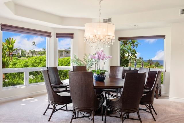 carpeted dining space with an inviting chandelier