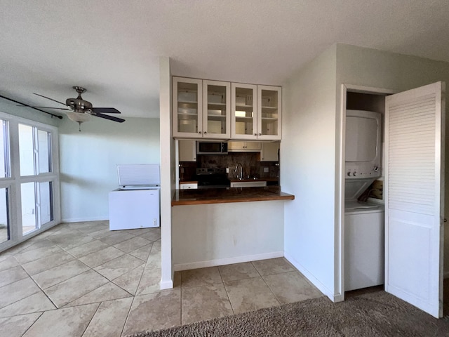 kitchen with ceiling fan, tasteful backsplash, stacked washer and dryer, light tile patterned flooring, and appliances with stainless steel finishes