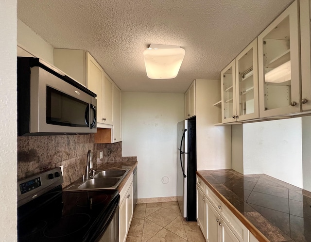 kitchen featuring backsplash, white cabinets, sink, light tile patterned floors, and stainless steel appliances