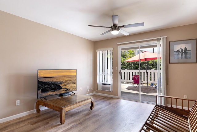 living area with light hardwood / wood-style floors, ceiling fan, and cooling unit