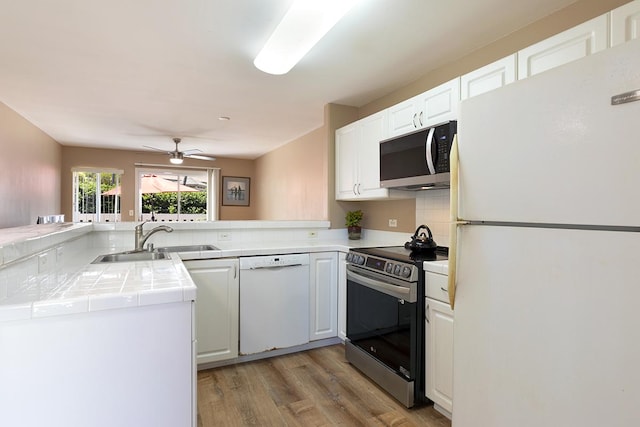 kitchen featuring white cabinets, kitchen peninsula, sink, and appliances with stainless steel finishes