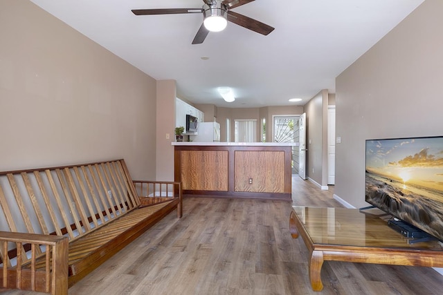 living area with ceiling fan and light hardwood / wood-style flooring