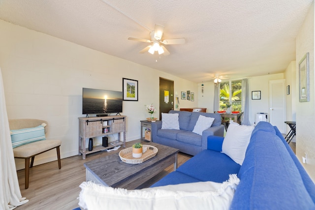 living area featuring a textured ceiling, ceiling fan, and light wood-style floors