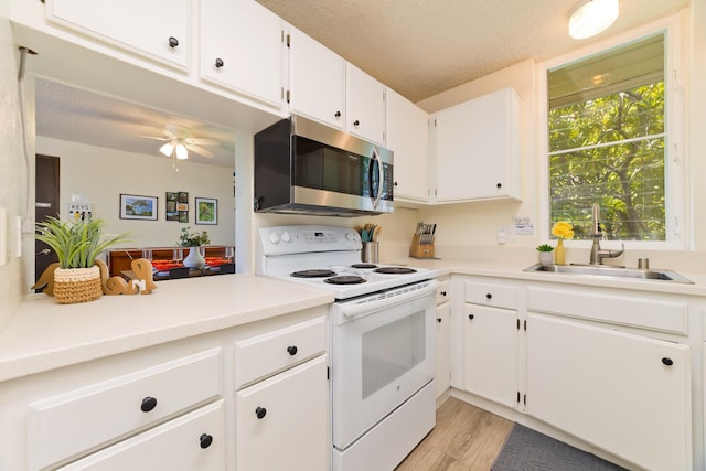 kitchen with a textured ceiling, light wood-style flooring, electric range, a sink, and stainless steel microwave