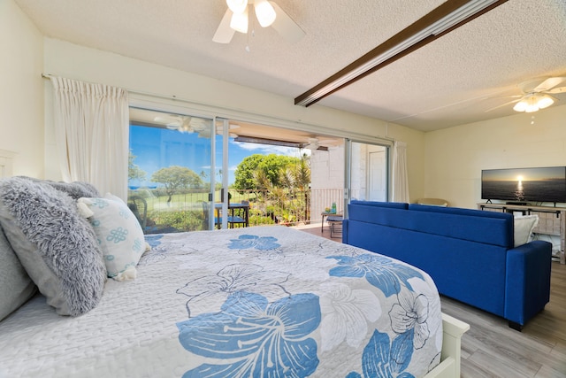 bedroom featuring access to exterior, a ceiling fan, a textured ceiling, and wood finished floors