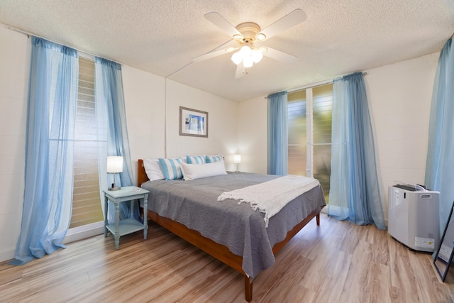 bedroom with a textured ceiling, ceiling fan, and light wood-type flooring