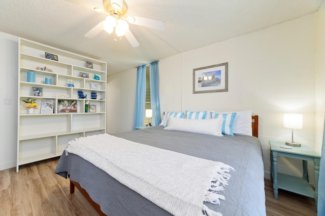 bedroom with a textured ceiling, a ceiling fan, and wood finished floors