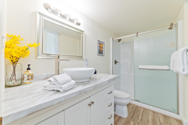 bathroom with a stall shower, vanity, toilet, and wood finished floors