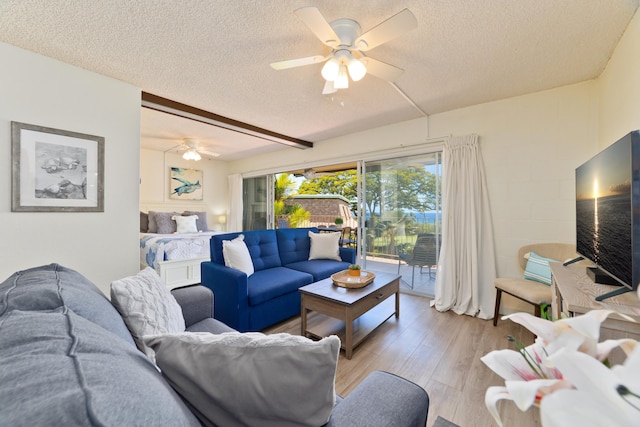 living room with a ceiling fan, light wood-type flooring, a textured ceiling, and concrete block wall