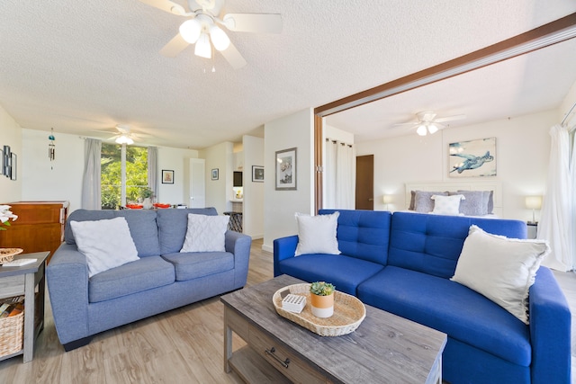 living room with a textured ceiling, ceiling fan, and light wood finished floors