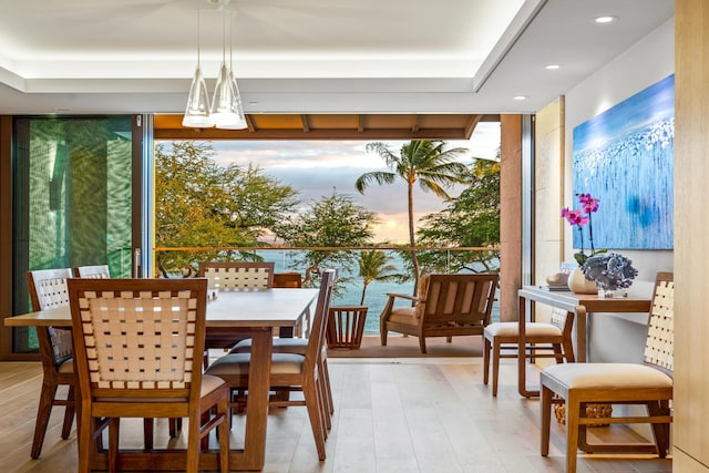 dining area featuring light hardwood / wood-style flooring, expansive windows, and a water view