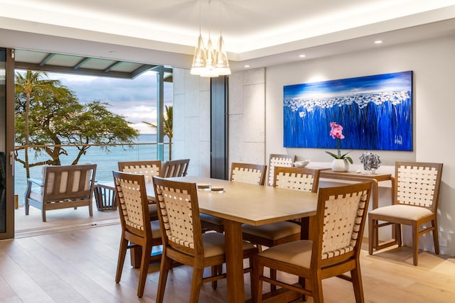 dining room with light hardwood / wood-style floors and a water view