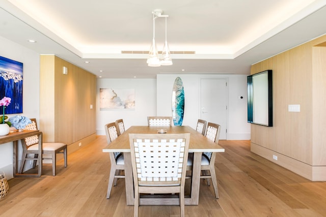 dining room with light wood-type flooring and a tray ceiling