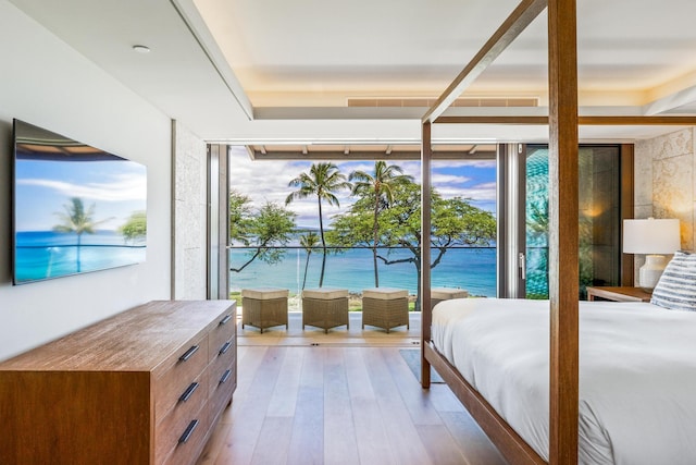 bedroom featuring a water view, a wall of windows, and light hardwood / wood-style floors