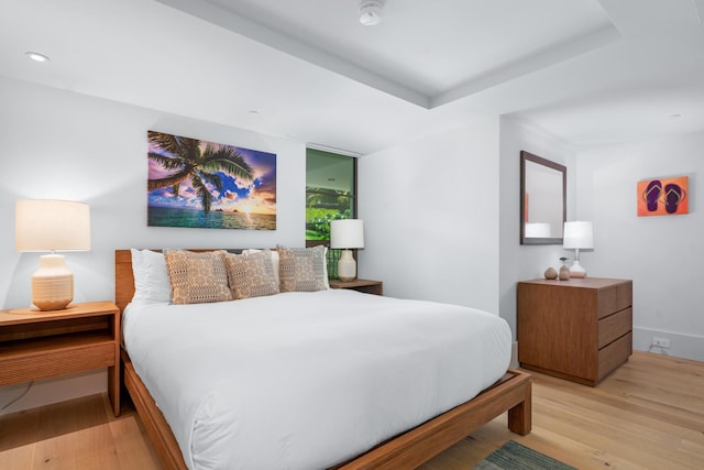 bedroom featuring a raised ceiling and light hardwood / wood-style floors