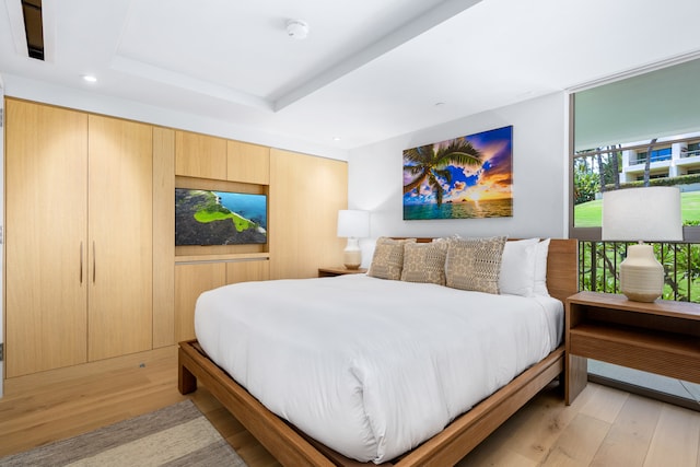 bedroom with a tray ceiling and light hardwood / wood-style flooring