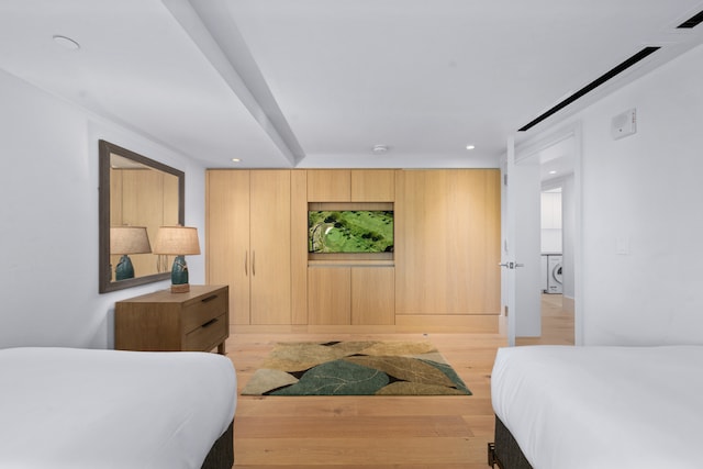 bedroom featuring stacked washer and clothes dryer and light wood-type flooring