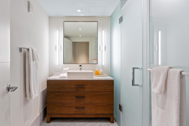 bathroom featuring a shower with door and vanity