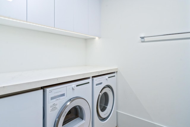 clothes washing area featuring washing machine and dryer and cabinets