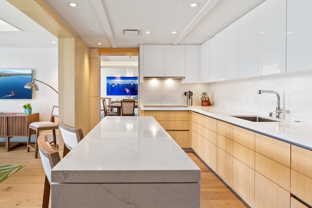 kitchen featuring sink, light hardwood / wood-style flooring, a center island, and white cabinets