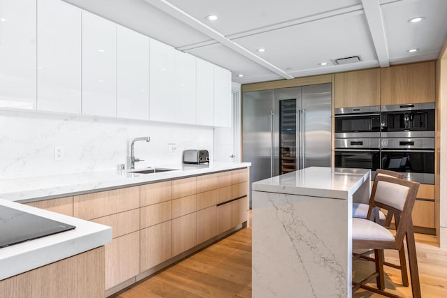 kitchen featuring sink, stainless steel appliances, a kitchen breakfast bar, white cabinets, and light wood-type flooring