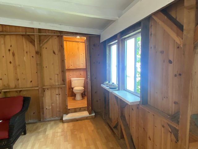 bathroom featuring toilet, wooden walls, and hardwood / wood-style flooring