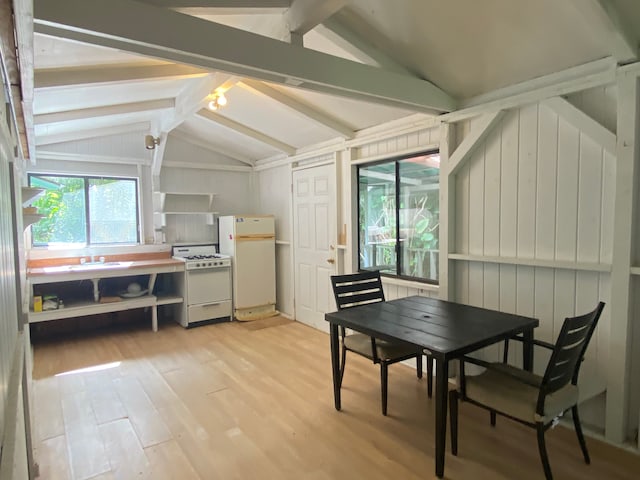 dining space featuring vaulted ceiling with beams and light hardwood / wood-style flooring