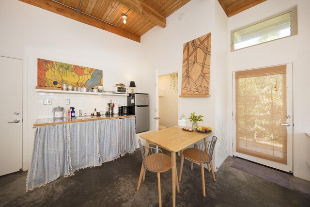 dining area with beamed ceiling, wooden ceiling, and a high ceiling