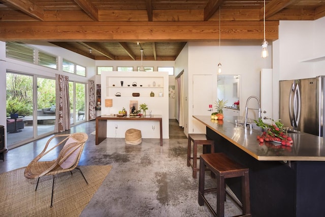 kitchen with finished concrete floors, freestanding refrigerator, decorative light fixtures, and dark countertops