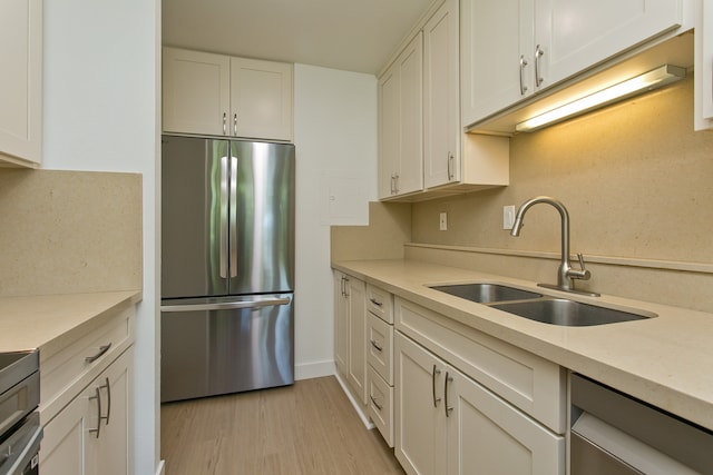 kitchen with stainless steel appliances, light hardwood / wood-style flooring, white cabinets, and sink